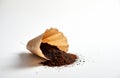 Brown paper coffee filter spilled on white surface. Ground coffee scattered around the filter. Minimalist studio shot. This image Royalty Free Stock Photo