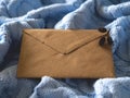 The brown paper envelope on the pale blue wool knitted background. Royalty Free Stock Photo