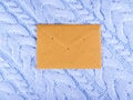 The brown paper envelope on the pale blue wool knitted background. Royalty Free Stock Photo