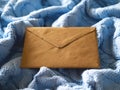 The brown paper envelope on the pale blue wool knitted background. Royalty Free Stock Photo