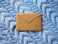 The brown paper envelope on the pale blue wool knitted background. Royalty Free Stock Photo