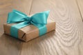 Brown paper gift box with blue ribbon bow on oak table Royalty Free Stock Photo