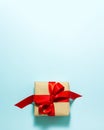 Brown paper gift box with a red satin ribbon bow on top on blue background. Christmas holiday mother and father Valentines days Royalty Free Stock Photo