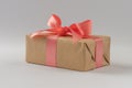 Brown paper gift box with silk rose ribbon on gray background