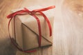 Brown paper gift box with thin red ribbon bow on old wood table with copy space Royalty Free Stock Photo