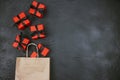 Brown paper shopping bag and red gift boxes with black ribbons on black  background Royalty Free Stock Photo