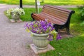 A brown Park bench and two vases of flowers