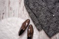 Brown patent leather shoes on a white fur, gray coat, a wooden background. Fashion concept