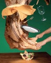 A brown patterned tablecloth, plate, fork, wine glass, and salad bowl float in midair. Two hands are visible grasping the Royalty Free Stock Photo