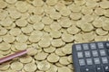 Brown pencil with black calculator on stack of gold coins Royalty Free Stock Photo