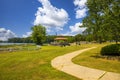 A brown pergola in the park surrounded by lush green trees, grass and plants with a blue lake and a smooth winding footpath Royalty Free Stock Photo