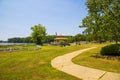 A brown pergola in the park surrounded by lush green trees, grass and plants with a blue lake and a smooth winding footpath Royalty Free Stock Photo