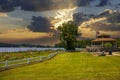 A brown pergola in the park surrounded by lush green trees, grass and plants with a blue lake and a smooth winding footpath Royalty Free Stock Photo