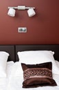 Brown pillow on bed with wall lighting