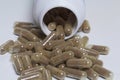 Brown pills are poured on a white surface from a plastic jar. Royalty Free Stock Photo