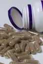 Brown pills are poured on a white surface from a plastic jar. Royalty Free Stock Photo
