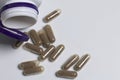 Brown pills are poured on a white surface from a plastic jar. Royalty Free Stock Photo