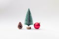 Brown pinecone with green and snow new year Christmas tree and red gift box stand next to each other on white pastel background. Royalty Free Stock Photo