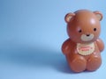 Brown Plastic bear piggy bank, isolated in blue background, studio shoot day time, valentine mood.