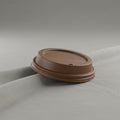 A brown plastic coffee cup lid rests on a smooth, light gray fabric surface. The lid is Royalty Free Stock Photo