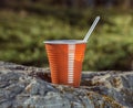 Brown plastic coffee cup with a spoon on a rock Royalty Free Stock Photo