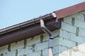 Brown plastic gutter pipe on white brick wall Royalty Free Stock Photo