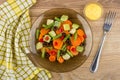 Brown plate with vegetable mix, napkin, bowl with sauce