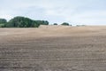 Brown ploughed field under cloudy sky after harvest