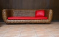 Brown Rattan Wicker Sofa with Red Leather Upholster and Pillow.