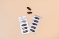 Brown rectal pills or suppositories for anal or vaginal use with blister on beige background. Medicines for alternative