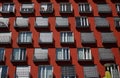 The brown-red facade of a residential building with many large windows and small balconies. The shutters are partially closed. It Royalty Free Stock Photo