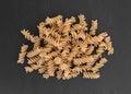 Brown rice pasta fusilli on a slate background