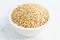 Brown rice in white bowl on white background. Dried cereals in cup, vegan food, fodmap diet. Side view, close up Royalty Free Stock Photo