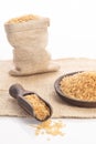 Brown rice on a wooden plate and spoon , and burlap sack on white backround Royalty Free Stock Photo