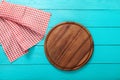 Brown round cutting board for pizza on red plaid tablecloth. Blue wooden table in the restaurant. copy space. Royalty Free Stock Photo