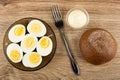 Brown saucer with halves boiled eggs, fork, bowl with mayonnaise, bread on table. Top view Royalty Free Stock Photo