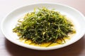 brown seaweed salad with soy sauce dressing on a white plate Royalty Free Stock Photo