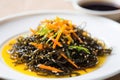 brown seaweed salad with soy sauce dressing on a white plate Royalty Free Stock Photo