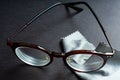 Brown shortsighted or nearsighted eyeglasses with microfibre cleaning cloths, On black background, Optical concept