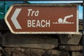 Brown sign beach in English and Irish language and pointing arrow