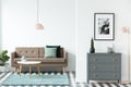 Brown sofa with green cushions standing in white open space living room interior with wooden table on carpet, grey Royalty Free Stock Photo