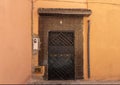 Brown steel door surrounded by bricks with a small tiled roof overhang in the old medina of Marrakesh, Morocco.