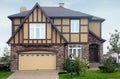 Brown stone cottage with beige garage and roof.