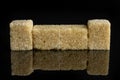 Brown sugar cube isolated on black glass Royalty Free Stock Photo