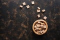 Brown sugar cubes in a bowl on a dark background. Top view, space for your text