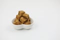 Brown sugar cubes on a love shape plate woman hand hold a wooden tweezers on white background Royalty Free Stock Photo