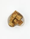 Brown sugar cubes on a love shape plate woman hand hold a wooden tweezers on white background Royalty Free Stock Photo