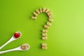 Brown sugar cubes shaped as a question mark over greenery background and two white spoons with heart on one of them. Top