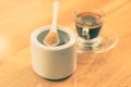 Brown sugar in a white ceramic spoon sitting on top of white ceramic container with blur coffee cup in background Royalty Free Stock Photo