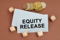 On a brown surface are coins, cubes and a business card with the inscription - Equity Release